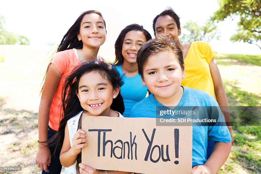 Confident kids in the park with 'Thank You!' sign