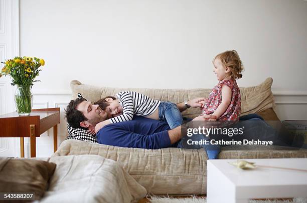 a dad playing with his children on a sofa - two kids playing with hose stock-fotos und bilder