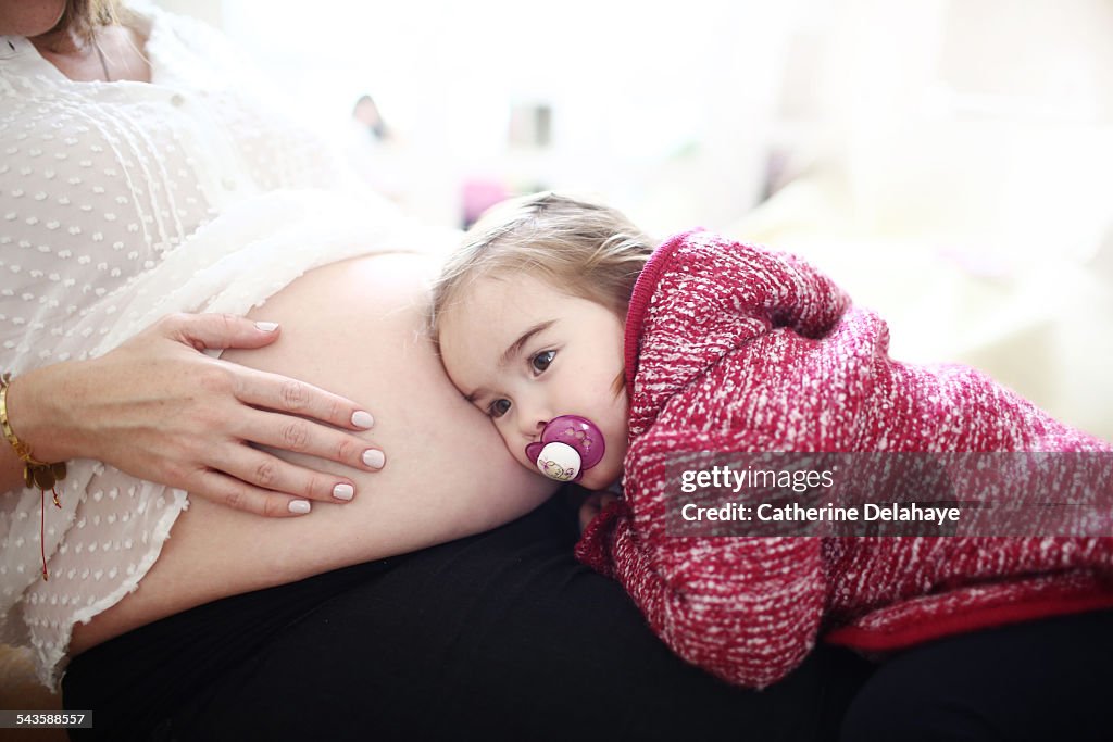 A 2 years old girl on the womb of her pregnant mom