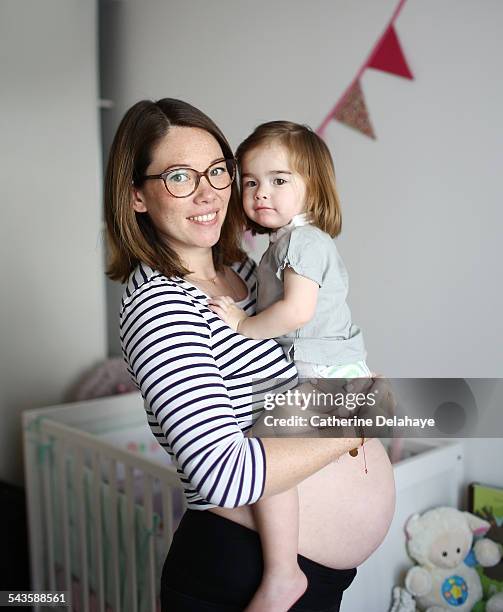 a pregnant mom with her 2 years old girl - woman 30 years old portrait stock pictures, royalty-free photos & images
