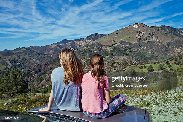 mother and daughter sitting on a car hood - サンタイネス ストックフォトと画像