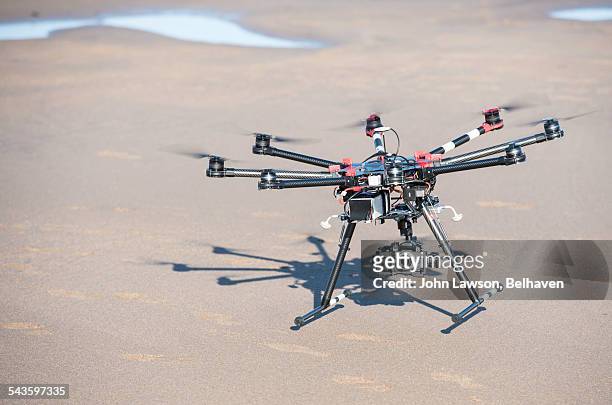 an octocopter drone comes into land on a beach - octocopter stock pictures, royalty-free photos & images