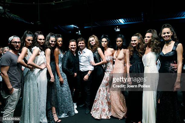Guido Maria Kretschmer and Andre Maertens pose with models backstage after the Guido Maria Kretschmer show during the Mercedes-Benz Fashion Week...