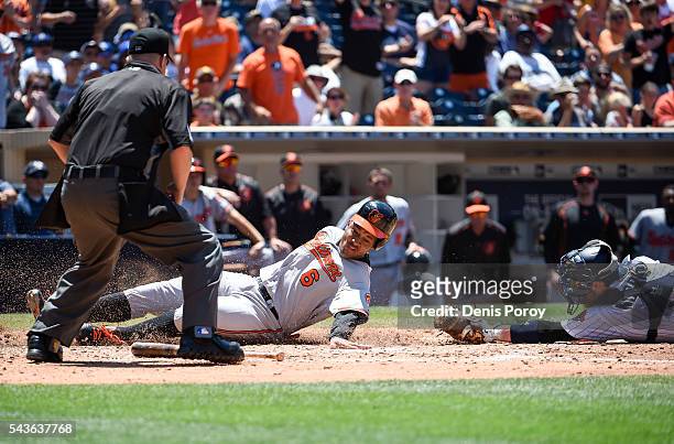 Jonathan Schoop of the Baltimore Orioles scores ahead of the tag of Derek Norris of the San Diego Padres during the fifth inning of a baseball game...