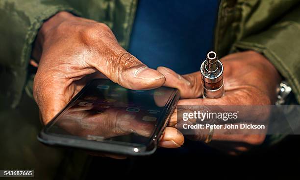 Checking a cellphone on a lunch break whilst having a smoke on an electric cigarette.