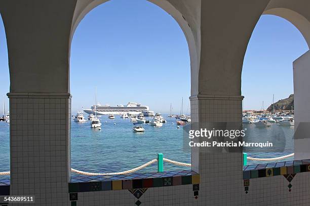 View of Avalon Harbor boats, yachts, and a cruise ship through tiled, arched windows on Catalina Island, California.