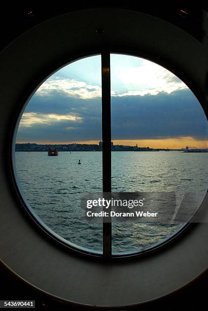 The Atlantic Ocean is seen on the shore of Staten Island, New York through a large round window of a cruise ship