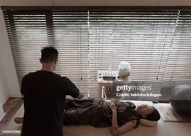 japanese female talking about acupuncture treatment with expert kyoto japan - man electric chair stock pictures, royalty-free photos & images