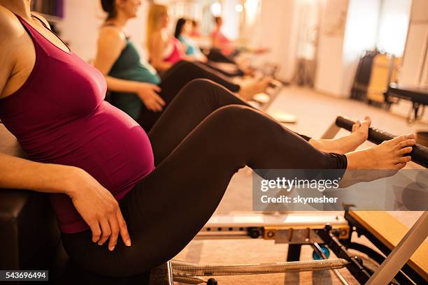 unrecognizable pregnant woman exercising during pilates class in health club. - pilates machine stock pictures, royalty-free photos & images