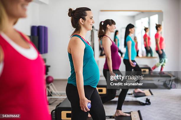 smiling pregnant woman doing prenatal pilates exercises in health club. - relaxation exercise stock pictures, royalty-free photos & images