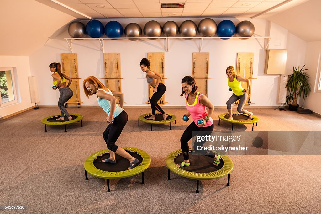 Eine Gruppe von Frauen Pilates-Training mit Gewichten auf Trampolinen.