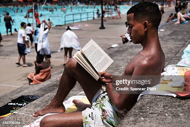 Emilo Moreno reads by the pool on a hot afternoon at the Astoria Pool in the borough of Queens on the opening day of city pools on June 29, 2016 in...