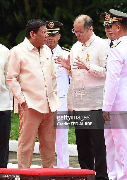 Outgoing Philippines President Benigno Aquino gestures as he talks to his successor Rodrigo Duterte during the departure ceremony for Aquino ahead of...