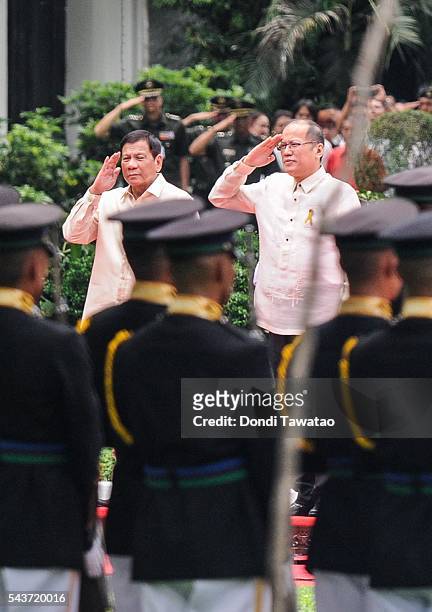 President-elect Rodrigo Roa Duterte and outgoing president Benigno Aquino III salute presidential honor guards during the inauguration at Malacanang...