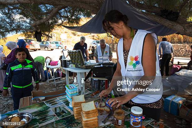 Volunteer helps to feed Syrian migrants that have just landed from Turkey, smuggled by people traffickers on the island of Lesbos. The migrants are...