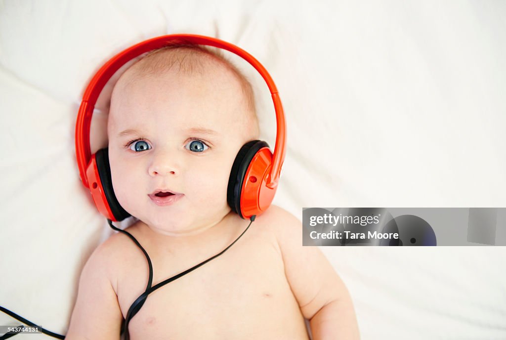 Baby with headphones in bed at home