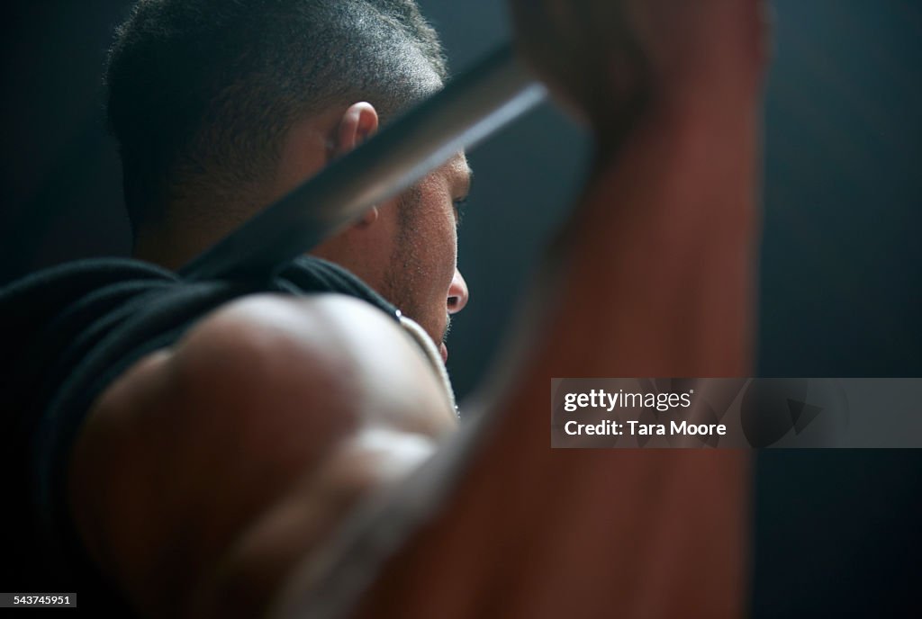 Male athlete lifting weight bar black background