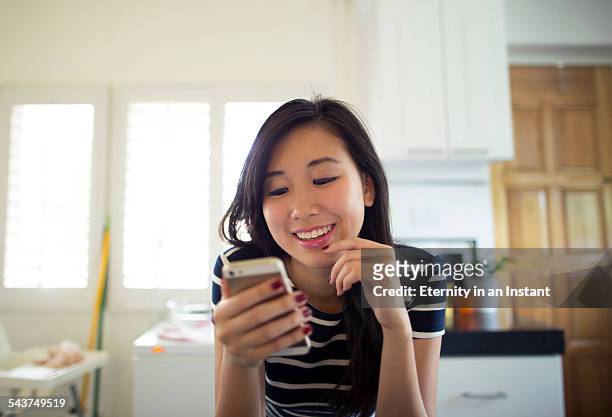 young woman looking at smart phone at home - singapore people stock-fotos und bilder
