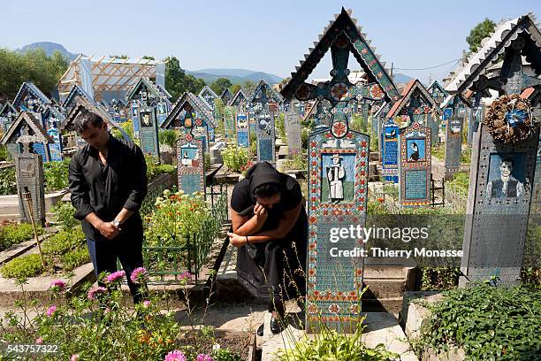 Sapânta, Maramures, Romania - An old woman is crying in front of a grave in the Merry Cemetery of Sapanta The first wooden cross where designed by...
