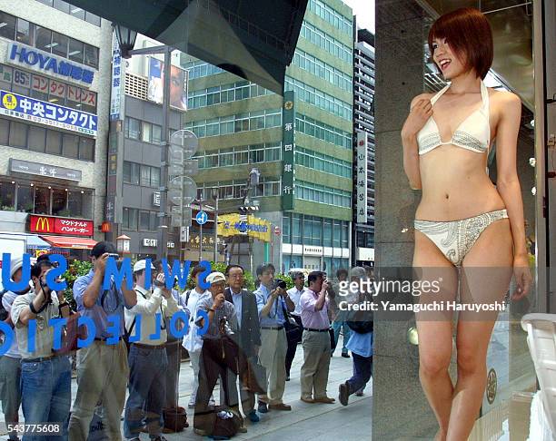 Swimwear models draw admining stares of window shoppers, and nearly stop noon day traffic in Tokyo, as they show off the latest swimwear in a display...