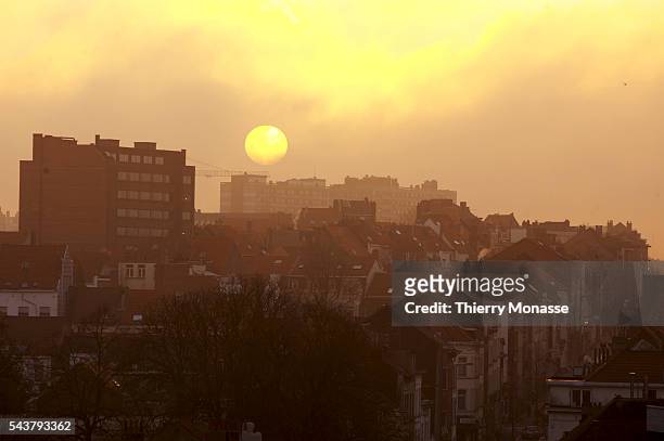Large orange sun rises over the Brussels skyline on a misty winter's morning.