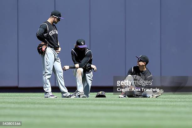 Brandon Barnes, Charlie Blackmon, and Carlos Gonzalez of the Colorado Rockies speak during a pitching change during the game against the New York...
