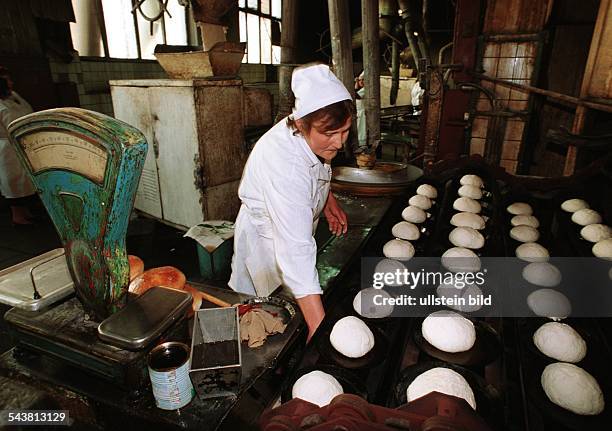 Eine Arbeiterin mit weißem Kittel und weißer Haube steht in der Brotfabrik Nr. 4 in Tiflis, Georgien, vor Backblechen mit Brot, das für den...
