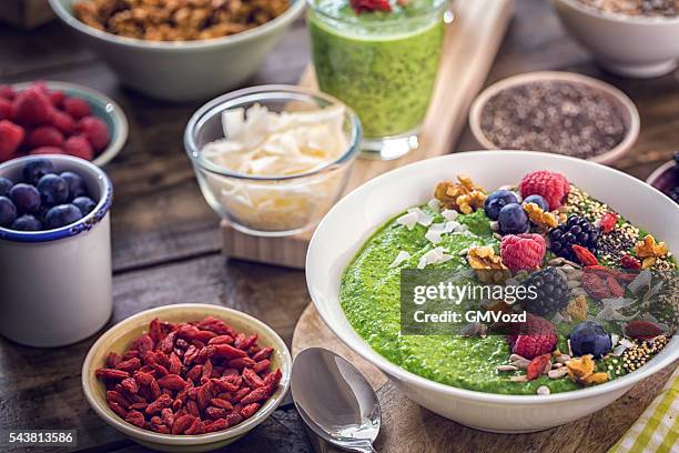 grün frühstück-smoothie in schüssel mit superfoods auf der oberseite - rohkosternährung stock-fotos und bilder