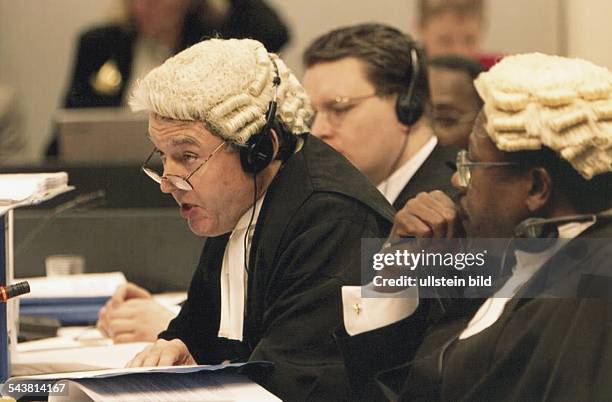 Der Kronanwalt am Seegerichtshof Hamburg, Richard Plender , trägt eine Haarbeutelperücke und Kopfhörer, die Brille sitzt auf der Nasenspitze. Auf dem...