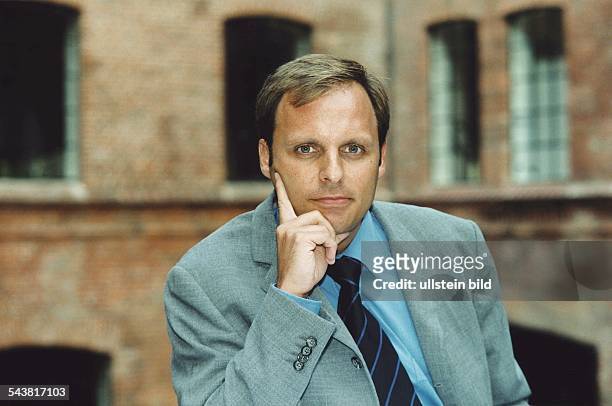 Der deutsche Gschäftsführer des Deutschen Sportfernsehens Rainer Hüther hat den Zeigefinger einer Hand an seine Wange gelegt. Aufgenommen August 1998.