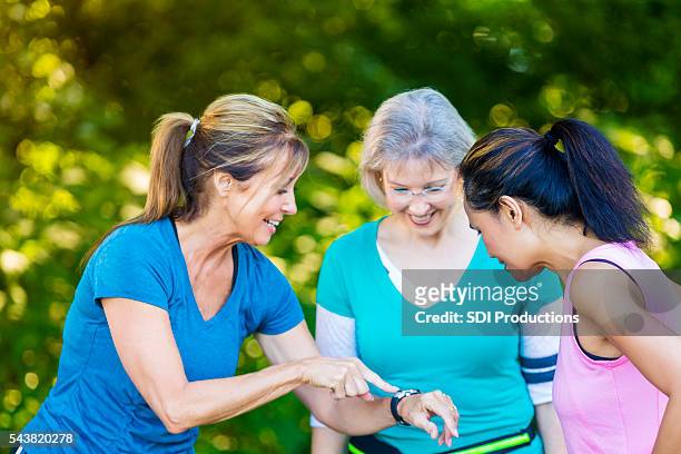 senior woman demonstrates her sports watch to friends - pedometer stock pictures, royalty-free photos & images