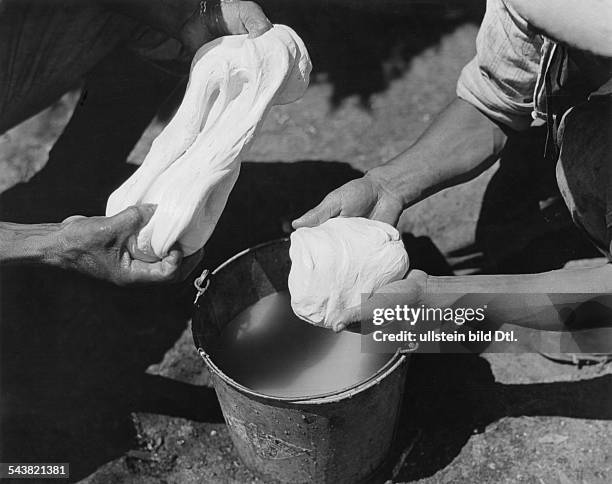 Mexico, Yucatan - Chicle hunters prepaing chicle lumps after boiling. Chicle-campabout 1931