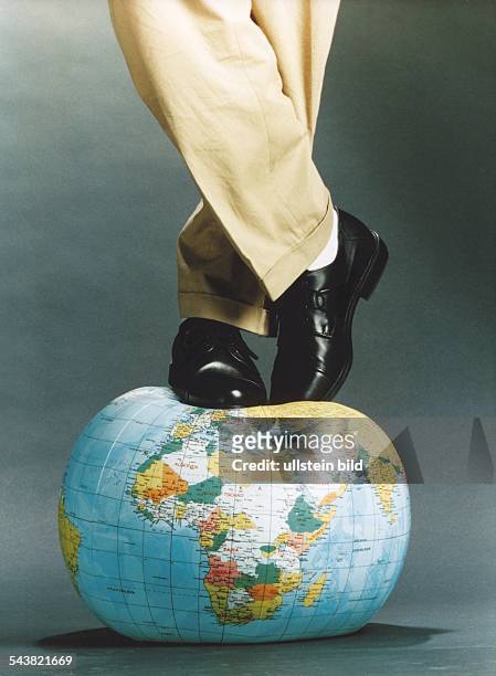 Ein Mann steht auf einer Weltkugel in Form eines aufblasbaren Wasserballs. Ökologische Gewalt, Umweltverschmutzung, Mensch und Umwelt. Symbolbild .