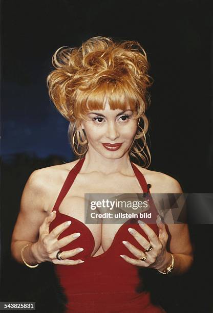 Die aus Prag stammende Pornodarstellerin sowie Porno-Produzentin Dolly Buster trägt ein rotes Oberteil mit tiefem Ausschnitt. An einem Träger, der um...