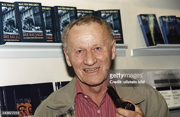 Der Autor Max von der Grün mit Pfeife in der Hand. Im Hintergrund auf einem Regal einige seiner Bücher mit dem Titel "Die Saujagd". Aufgenommen...