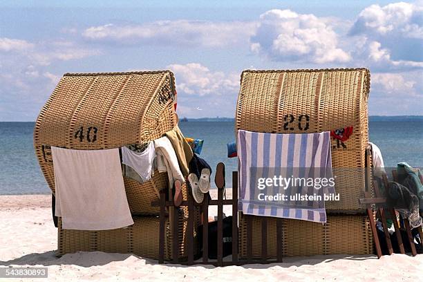 Strandkörbe, Rückansicht, am Strand der Ostsee. Nasse Wäsche und Badesachen trocknen im Wind. Urlaub; Ferien; Sommer; Sonne; schönes Wetter; Erholung.