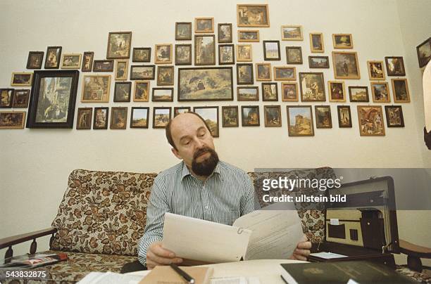 Der ostdeutsche Pfarrer Rainer Eppelmann, Mitglied der Partei "Demokratischer Aufbruch", sitzt in Unterlagen lesend in seinem Wohnzimmer. An der Wand...
