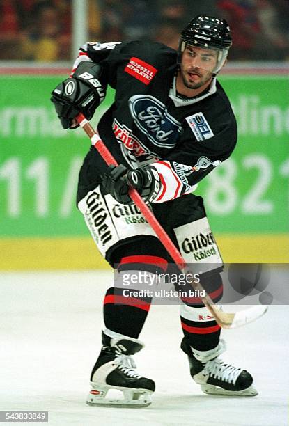 Der US-amerikanische Eishockeyspieler sowie Verteidiger bei der Eishockeymannschaft Kölner Haie Liam Garvey spielt den Puck mit seinem Stock. .