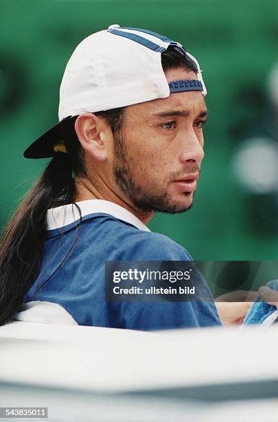 Der chilenische Tennisspieler Marcelo Rios von der Seite fotografiert, sitzend. Er trägt sein Markenzeichen: eine umgedrehte Schirmmütze. Seine...