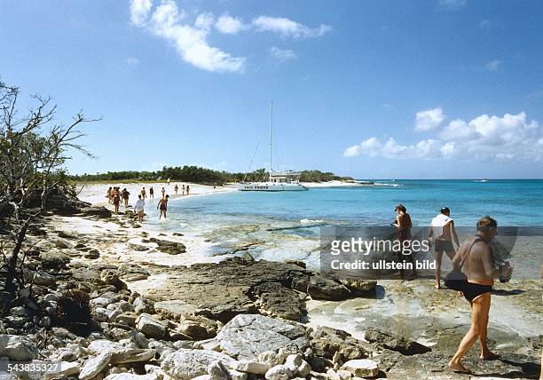 Karibik: Türkis blaues Meer und lange weiße Strände; Touristen gehen auf den Steinen spazieren. Aufnahmedatum:1999.