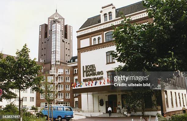 Der Eingangsbereich des Hotels und Restaurants "Hotel Hafen Hamburg" ist mit internationalen Flaggen geschmückt. Vor dem Eingang parkt ein blauer...