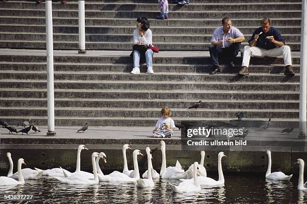 Hamburg.Sommer in der Hamburger Innenstadt: Auf den Stufen zur Kleinen Alster am Rathausmarkt entspannen junge Leute und essen Eis. Inmitten von...