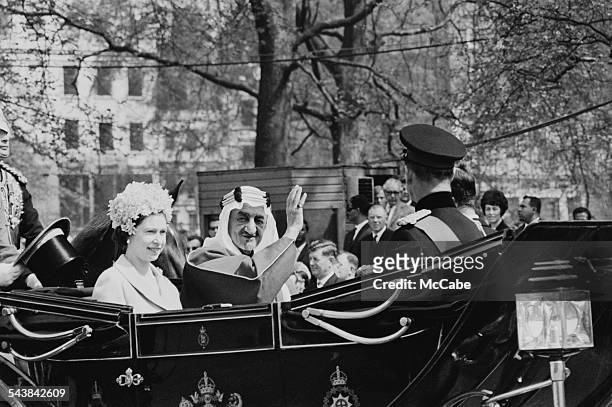 Queen Elizabeth II with King Faisal of Saudi Arabia travelling to Hyde Park for a military pageant by the King's Troop Royal Horse Artillery, London,...