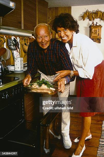 Der Schauspieler Hans Quest und seine Frau Ingrid in der Küche. Sie sind im Begriff eine Glasform mit Inhalt in den Backofen zu stellen. Im...