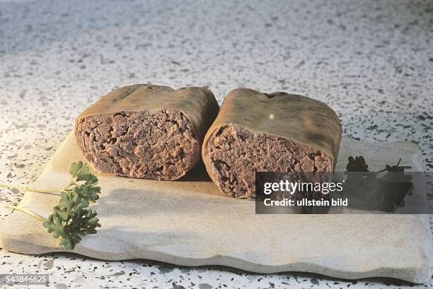 Angeschnittene Leberwurst auf einem Holzbrett mit Petersilie als Dekoration. .