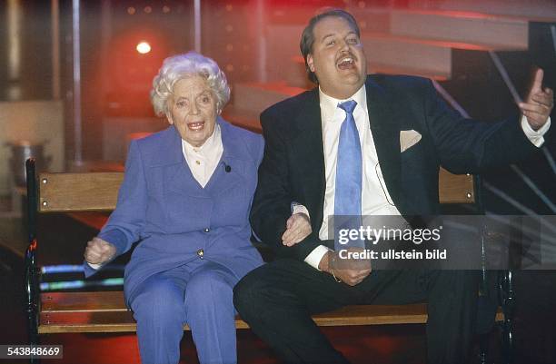 Schauspielerin Heidi Kabel und Entertainer Andreas Ellermann sitzen bei einem gemeinsamen Auftritt auf einer Bank und singen aus voller Kehle....