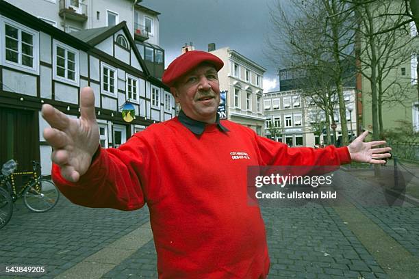 Joachim Winsmann, mit roter Baskenmütze und rotem Pullover, in einer Straße in Bergedorf. In dem neuen Projekt "City Meister" fungiert Winsmann als...