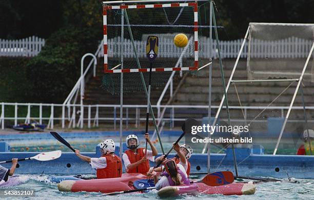 Kanupolo im Volksparkschwimmbad Hamburg. Spieler zweier Mannschaften kämpfen in ihren Kajaks im Wasser gefüllten Pool um den Ball. Mit erhobenen...