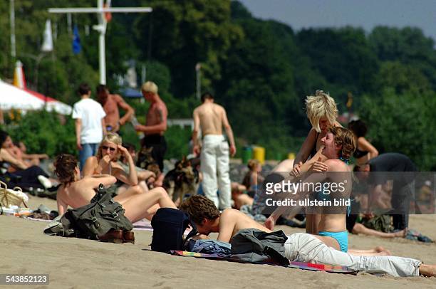 Hamburg, BRD: Menschen sonnen sich am Strand an der Elbe. .