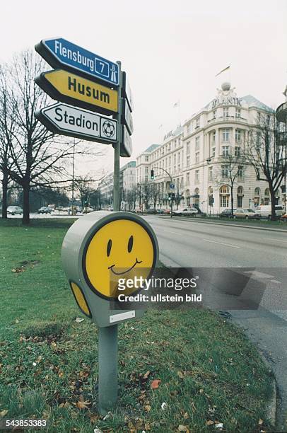 Sachbeschädigung / Vandalismus: Auf das gelbe Hinweisschild einer begrünten Hamburger Verkehrsinsel an der Alster ist ein Smiley gemalt worden....